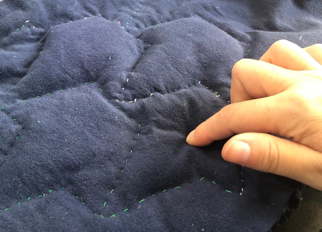 a finger squishing the overstuffed ivy sections from the lining (which makes the degree of stuffing easier to discern)