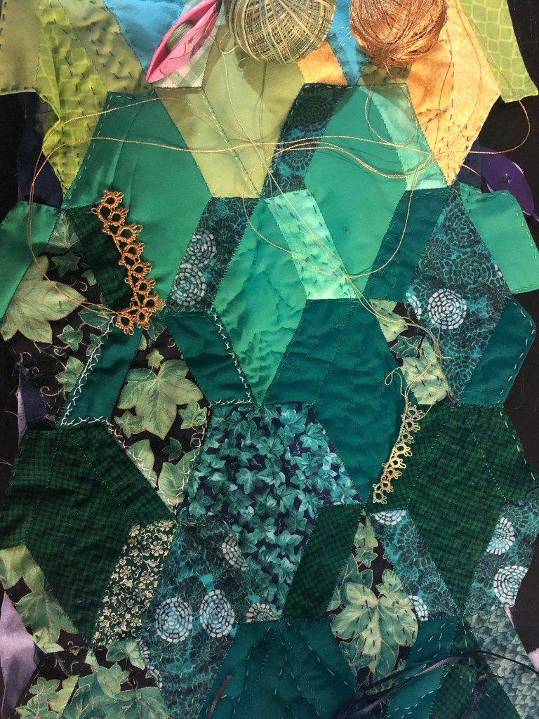patchwork with partially quilted lines of veins as well as lengths of lace along certain leaf edges. the tatting shuttles are still attached to the lace that is casually draped but not attached